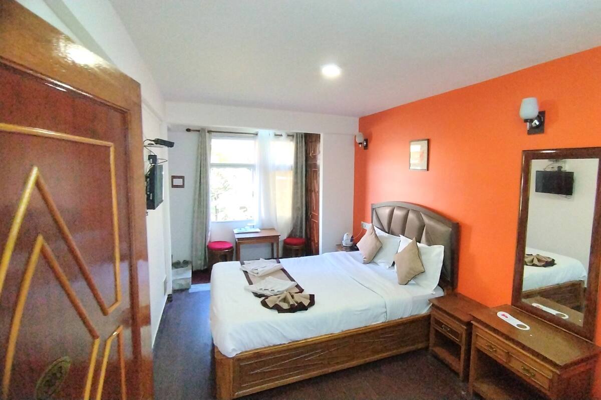 A bedroom with a bed, bedside table, and a mirror.