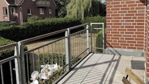 En balkon med gelænder, plantekasser og en træbænk.