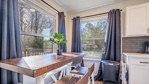Une cuisine avec une table en bois, une plante en pot et une vue sur l’extérieur.