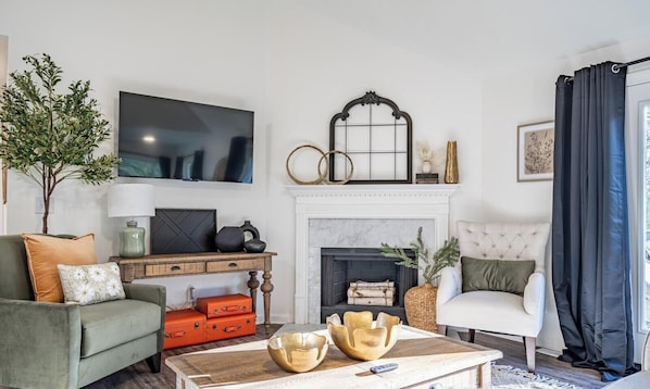 A living room with a fireplace, a television, a sofa, a coffee table, and a chair.