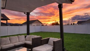 Un espacio de estar al aire libre con techo y vistas a un atardecer.
