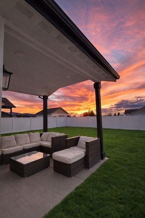 A covered outdoor seating area with a view of a sunset.