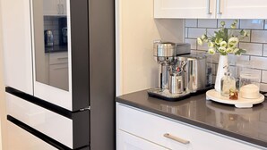 Una cocina moderna con armarios blancos, un refrigerador negro y una cafetera sobre la encimera.