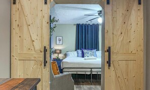 Ein Schlafzimmer mit einem Bett, einem Nachttisch, einer Lampe und einem Deckenventilator.