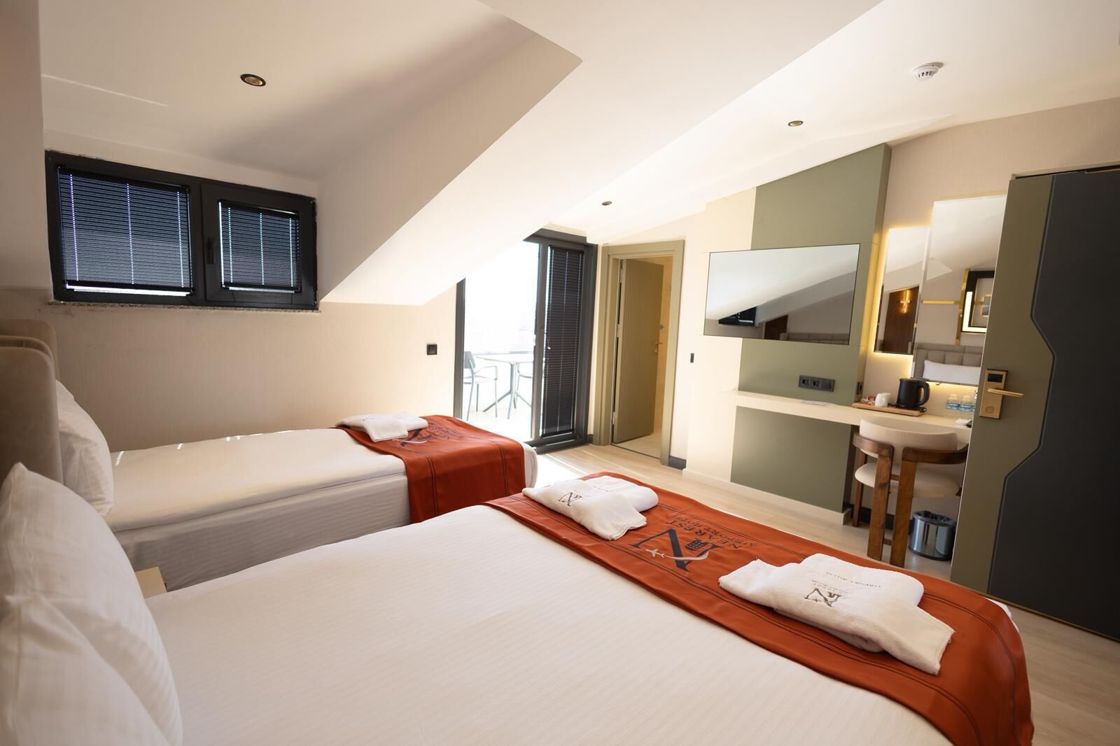 A hotel room with two beds, a bathroom, and a kitchenette.