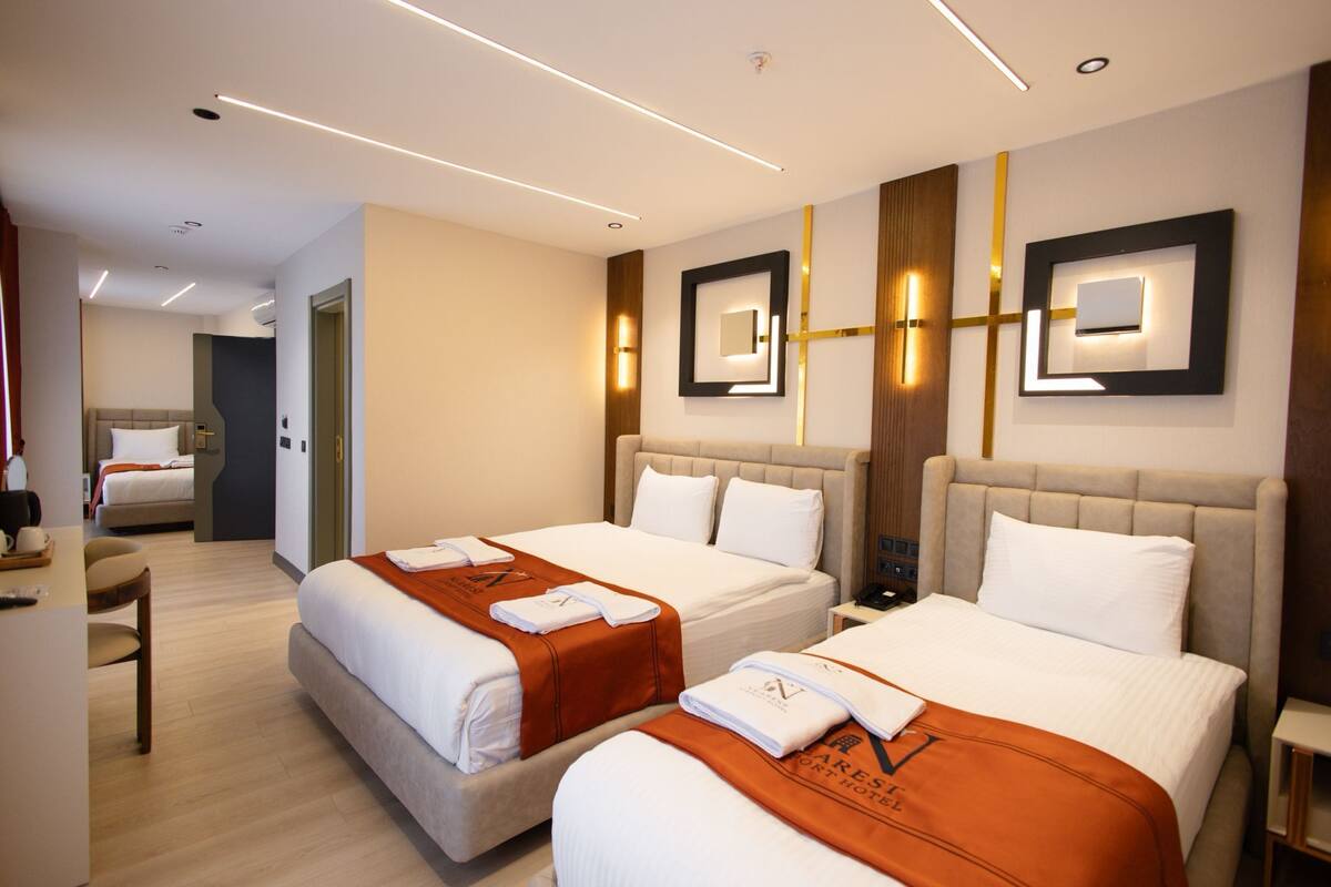 A hotel room with two beds, a desk, and a chair.