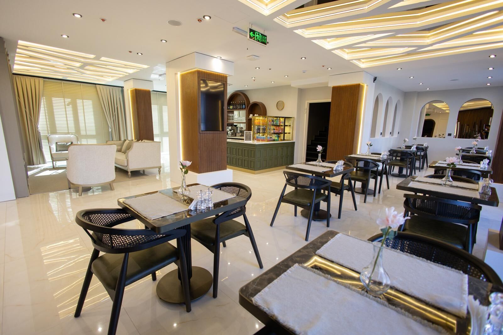 Un moderno vestíbulo de hotel con una zona de bar, arreglos de asientos y un mostrador de recepción.