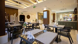 Een modern restaurantgedeelte in een hotel, met tafels, stoelen en een bar.