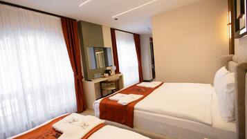 A hotel room with two beds, a desk, a mirror, and a television.