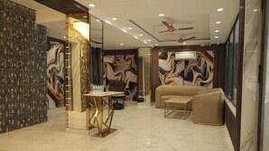 A modern lobby with a marble floor, a sofa, a table, and a ceiling fan. - Vardaan Residency Hotel (Gorakhpur)