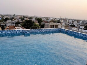 A rooftop swimming pool with a tiled edge, surrounded by residential buildings.