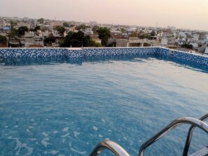 Una piscina con borde de azulejos, rodeada por un paisaje urbano.