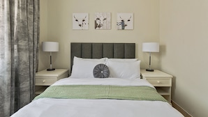Habitación de hotel con cama, dos mesitas de noche, cabecero y tres obras de arte colgadas en la pared.