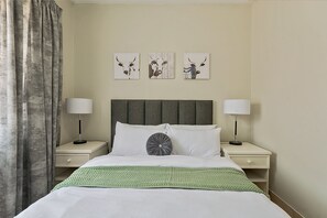 A hotel room with a bed, two bedside tables, a headboard, and three wall-mounted artworks. - Cozy Midrand Stay with Pool , Wi-Fi , Secure Parking&Self Checkin. (Midrand)