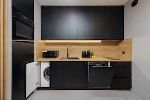 Una cucina compatta con lavatrice integrata, lavastoviglie e forno a microonde.