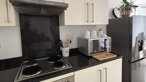 A kitchen with a stove, oven, microwave, toaster, and refrigerator.
