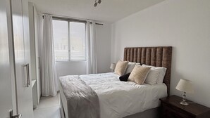 A bedroom with a bed, bedside table, lamp, and a patterned rug.