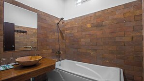 Une salle de bain avec un meuble-lavabo en bois, un grand miroir, une baignoire blanche et une douche équipée d’un pommeau de douche à main.