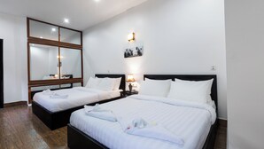 Une chambre d’hôtel avec deux lits, un grand miroir, un tableau accroché au mur et une table de chevet avec une lampe.