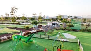 Un campo da golf con un'area giochi per bambini, che include uno scivolo e altalene.