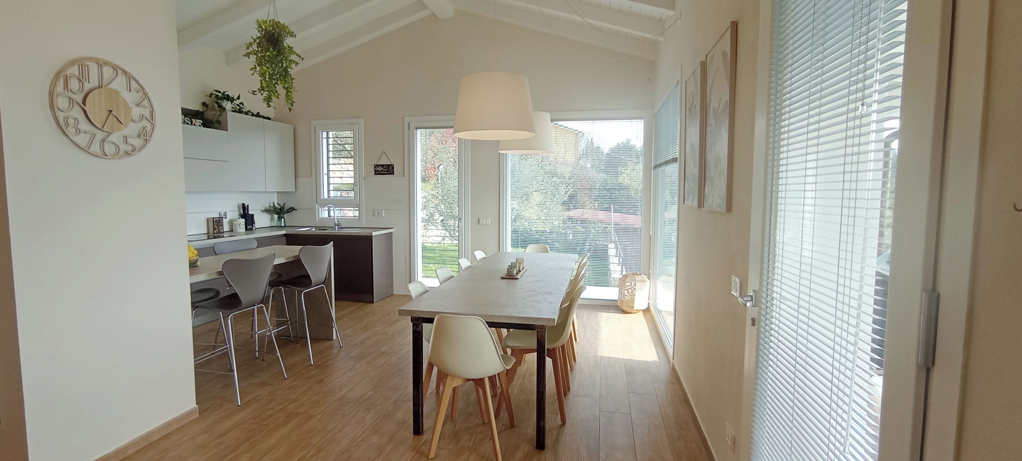 A modern kitchen with a dining area, wooden flooring, and a large window.