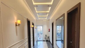 A hotel hallway with a marble floor, recessed lighting, and a central white carpet. - HOTEL NATRAJ (Sirsa)