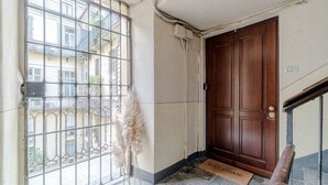 Ein Zimmer mit vergittertem Fenster, einer Holztür, einer Fußmatte und einer Treppe.