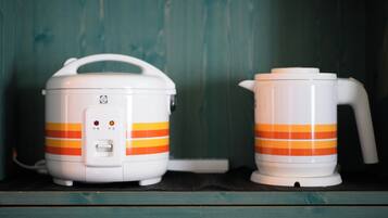 Two white appliances with orange stripes, a handle, and a control panel, placed on a shelf against a wooden background.
