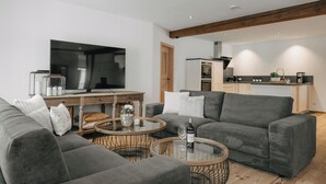 A modern living room with a grey sofa, a coffee table, and a TV. - Mika Hof exklusive Apartments (Weitnau)