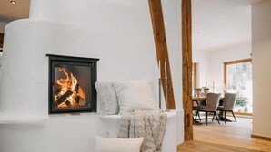 A cozy room with a fireplace, a dining area, and a view of the outdoors. - Mika Hof exklusive Apartments (Weitnau)