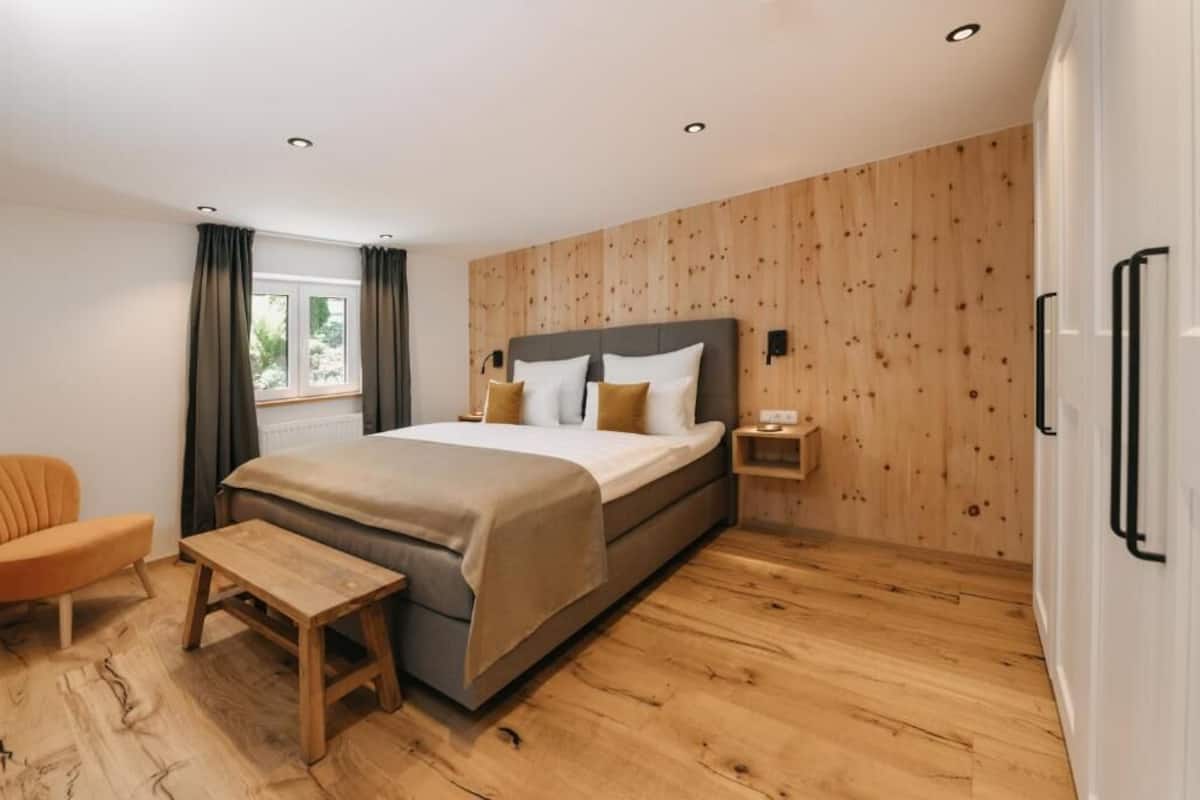 Ein modernes Schlafzimmer mit einem großen Bett, einer Wand aus Holzpaneelen und einem kleinen Nachttisch.