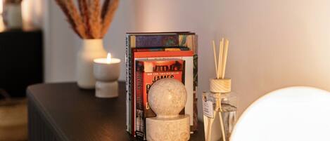 A bookshelf with books, a candle, and a decorative item on a dark wooden surface.