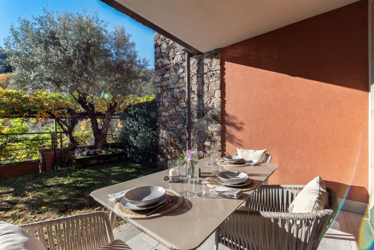 An outdoor dining area with a stone wall, wicker chairs, and a table set for two.