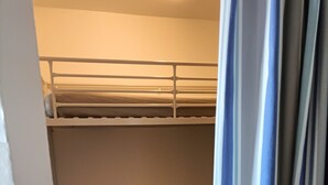Ein Schlafraum mit Etagenbetten, wobei ein Vorhang das Fenster teilweise verdeckt.