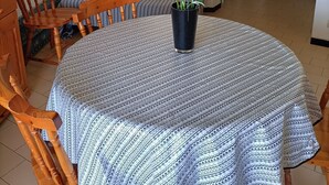 Ein Essbereich mit einem runden Tisch, Stühlen, einer Blumenvase, einer Couch und einer Wanduhr.