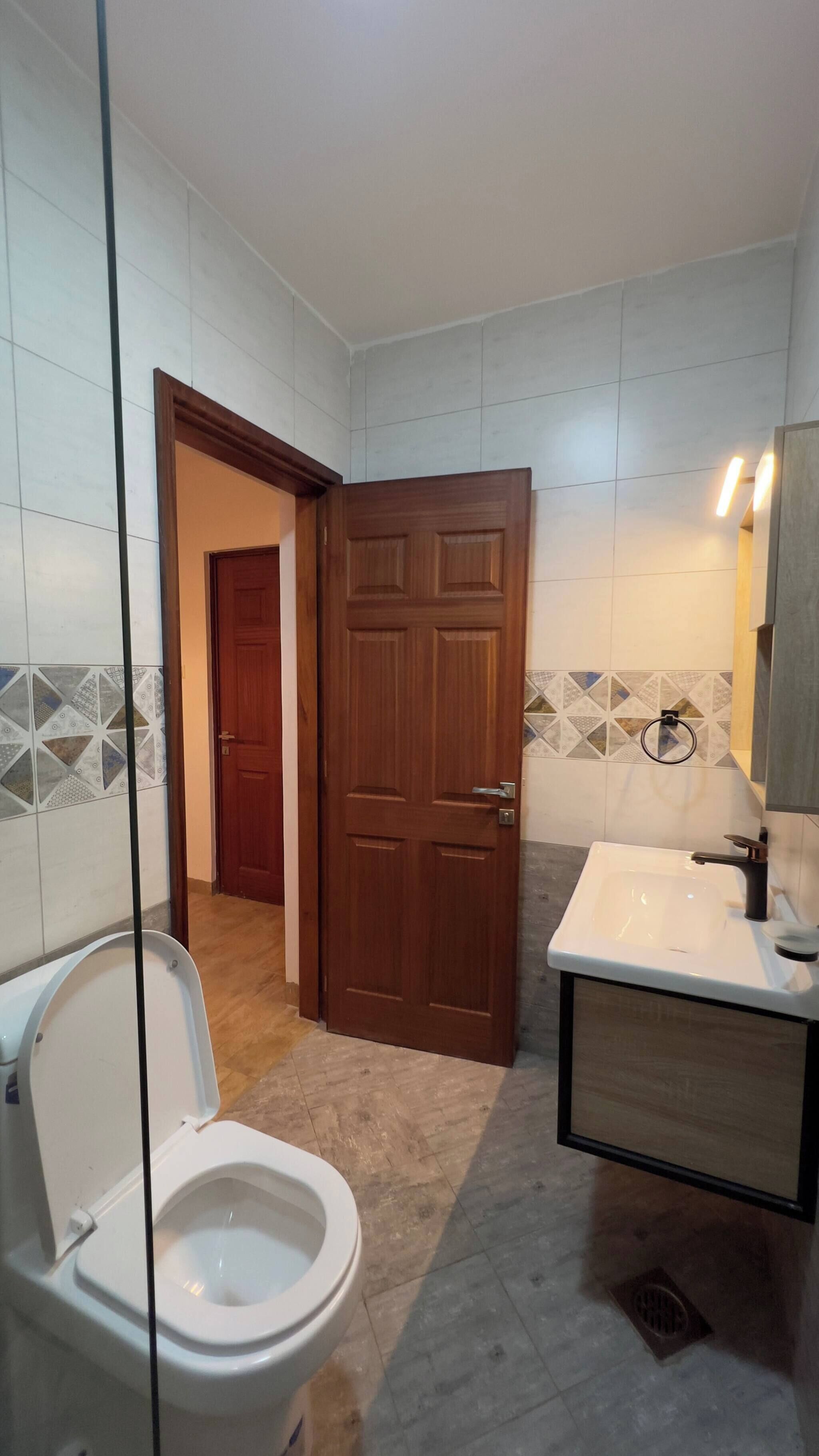 A bathroom with a toilet, sink, and a wooden door.