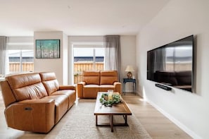 Una sala de estar con un sofá, una mesa de centro, un televisor y un cuadro en la pared.