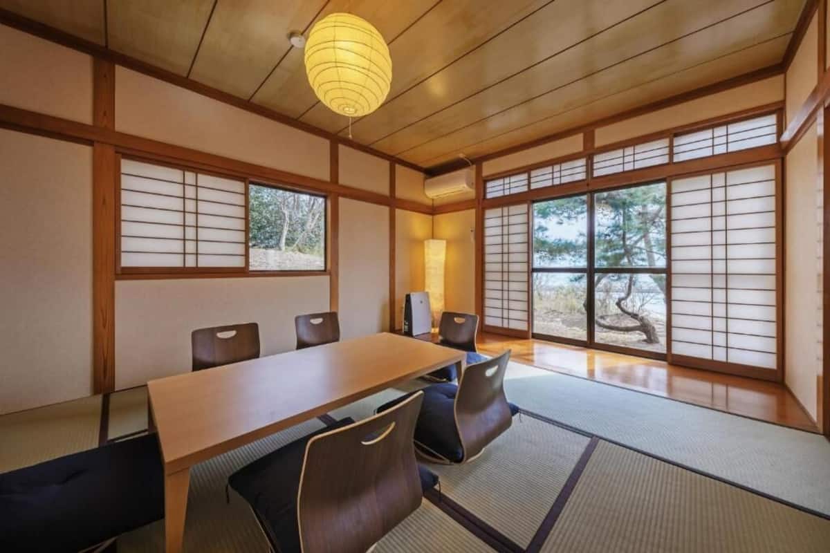 Una habitación japonesa tradicional con suelo de tatami, una mesa de madera baja y puertas correderas shoji.