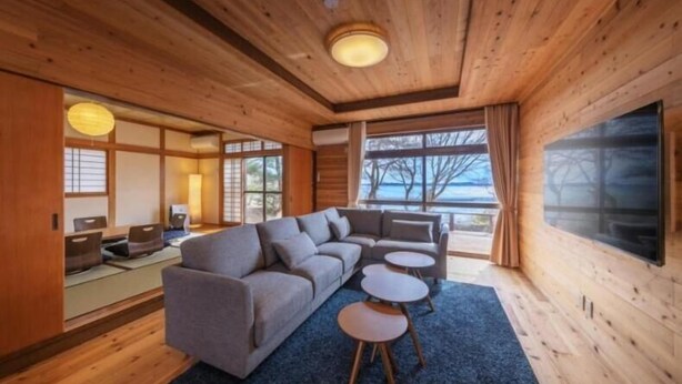 A modern interior with a sofa set, small round tables, and a large window.