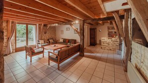 Un intérieur rustique avec des éléments en bois, un mur en pierre, un canapé, des fauteuils et une table à manger.