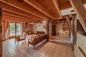 A rustic wooden interior with a stone wall, a sofa, chairs, and a dining table. - Gite authentique de charme Rocamadour (Trespoux-Rassiels)