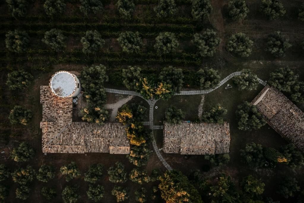 An aerial view of a property with a circular water tower, a rectangular building with a flat roof, and a paved pathway connecting them.