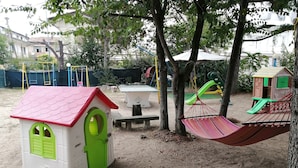 A playground with a small house, swings, and slides. - Euroholiday Village 5R Apartment with Private Terrace, Shared Garden, and Wi-Fi (Lido di Jesolo)