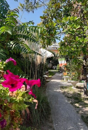 A garden pathway with plants and a flag. - Euroholiday Village 5R Apartment with Private Terrace, Shared Garden, and Wi-Fi (Lido di Jesolo)