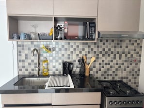 Keittiössä on mikroaaltouuni, liesi ja erilaisia keittiövälineitä.