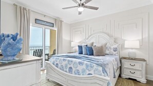 Quarto com cama, mesa de cabeceira e vista para o exterior.