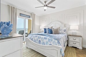 A bedroom with a bed, nightstand, and a view of the outdoors. - Gulf-Front Corner 3BR • Wrap Balcony • Sleeps 10 (Gulf Shores)