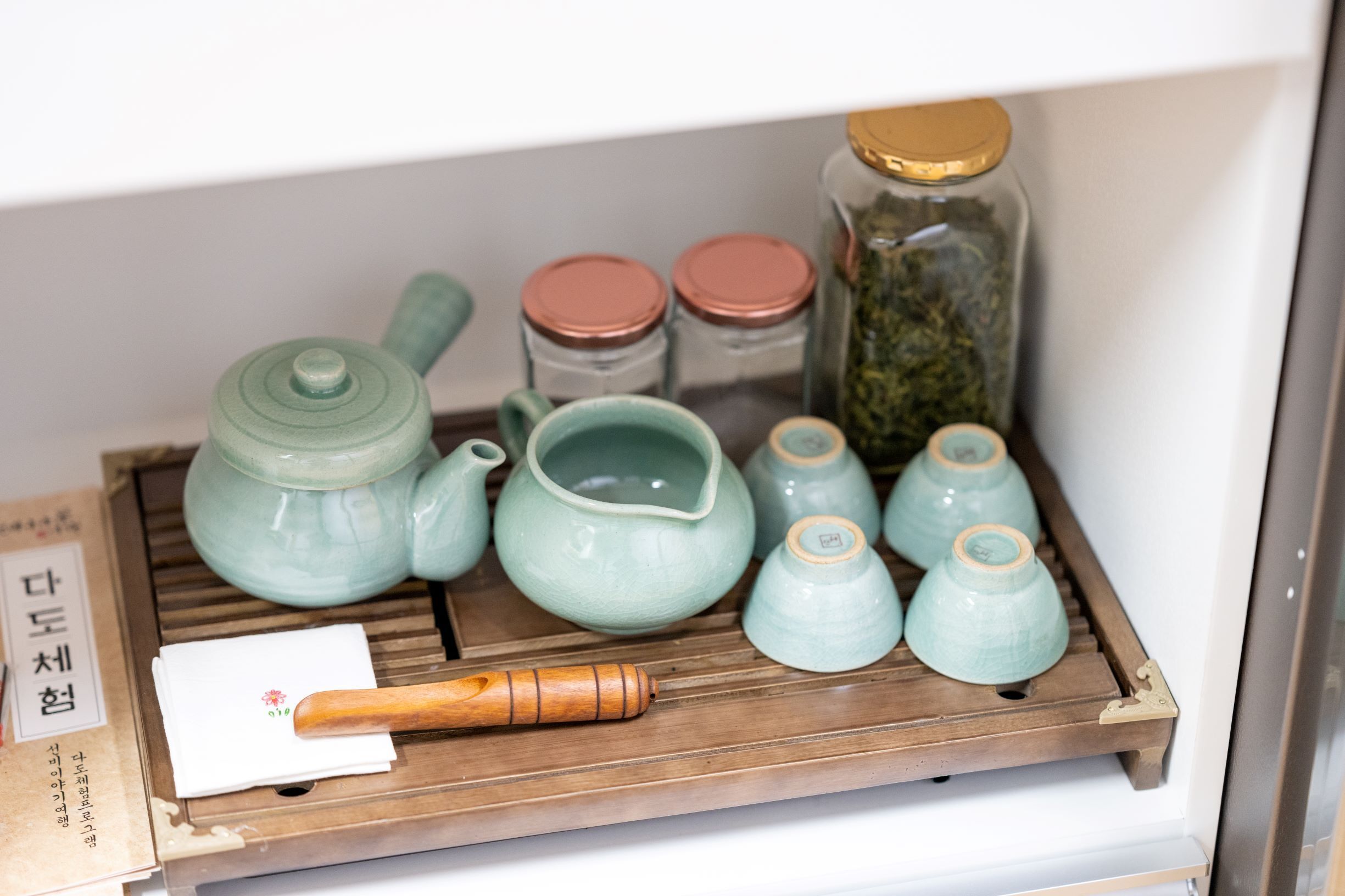 Una bandeja de madera con juego de té de cerámica y frascos.