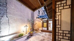 Ein traditioneller japanischer Innenhof mit Steinboden, Holzbalkendecke und einer Laterne.
