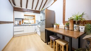 Eine Küche mit Holzbalken, weißen Schränken, einem Holztisch und Topfpflanzen.